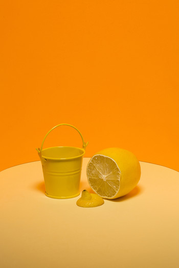 Натюрморт с жёлтым ведром и лимоном на оранжевом фоне
