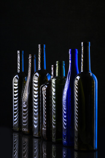 Натюрморт со стеклянными бутылками на чёрном фоне